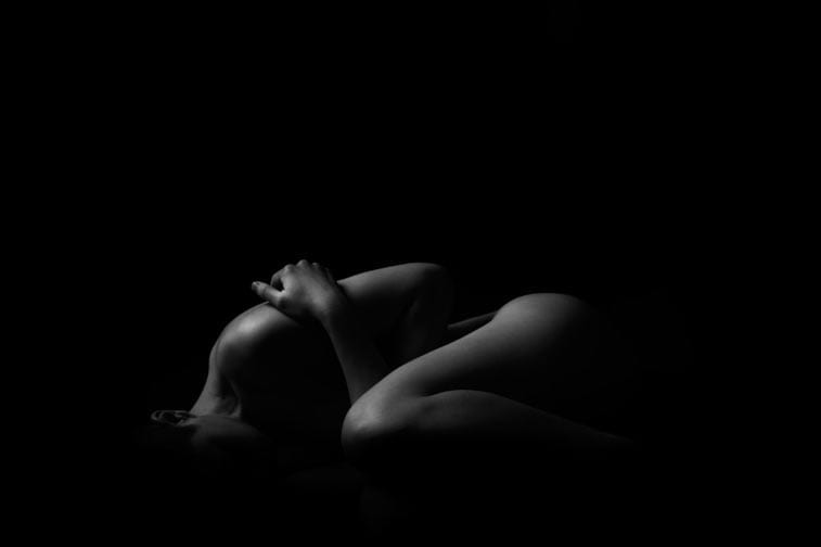 a woman in pain, black and white, curled up into a ball