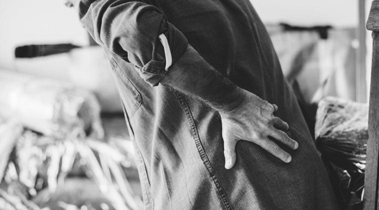 a slightly overweight man holds his back