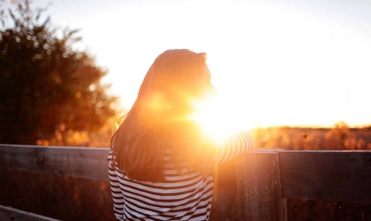 a woman with the sun in the background