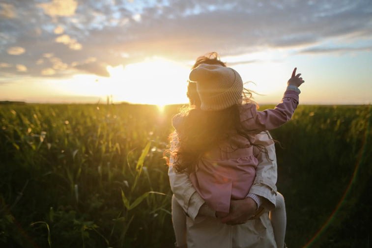 a woman holding her child in a field