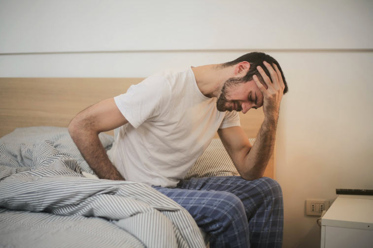 a man in bed suffering from fatigue